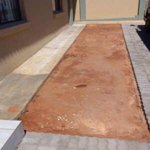 A completed installation of artificial turf in a residential backyard, with a patio set and BBQ grill in the background.